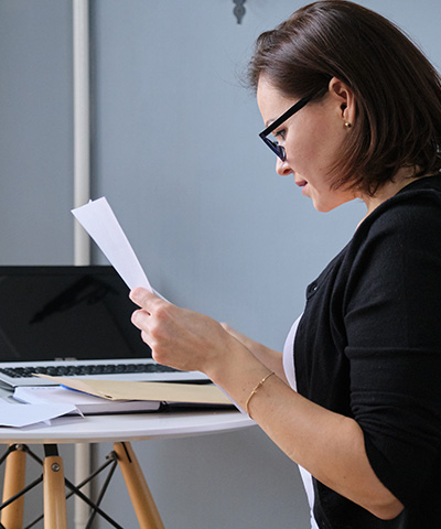 Empresaria vestida de sueter negro con gafas negras revisando sus estados de cuenta de la empresa, para gestionar cobro de cheque internacional