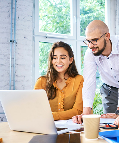 Pareja de emprendedores gestionando un pago a proveedor internacional con confirming, a través del ordenador