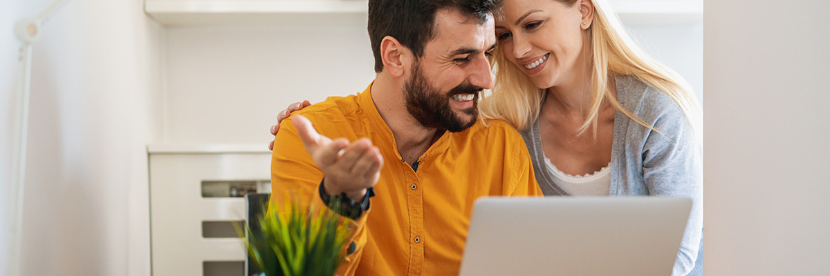 Fondos de inversión perfilados de Globalcaja Fondos de inversión perfilados - Chico y chica sonriendo viendo ordenador, planificando sus inversiones