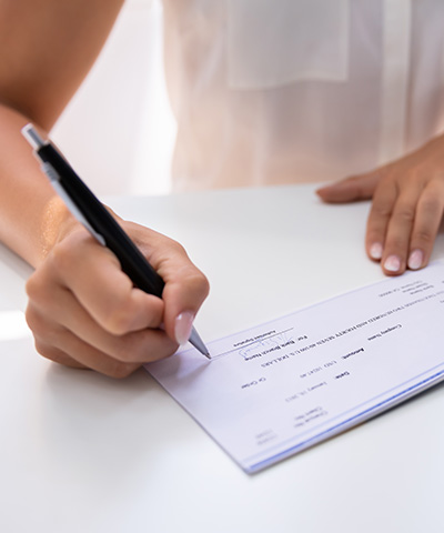 Beneficios de servicio de ingreso de cheques de manera online de Globalcaja Persona rellenando un cheque con un bolígrafo - Servicio de ingreso de cheques online