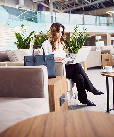 Beneficios de la Banca Patrimonial y del Club Exclusivo de Globalcaja - Mujer ejecutiva vestida de pantalón azul y camisa blanca, trabajando con ordenador en una sala exclusiva.
