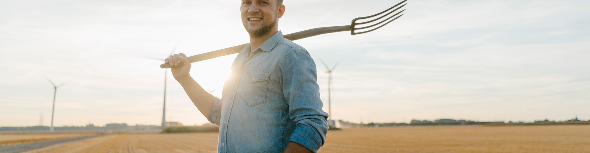 Financiación a largo plazo Agroinversión - Persona con camisa azul, en el campo con herramienta de trabajo para trabajar en granja