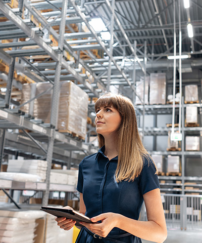 Beneficios del pago a proveedor con Confirming - Chica vestida de azul, supervisando almacén de empresa 