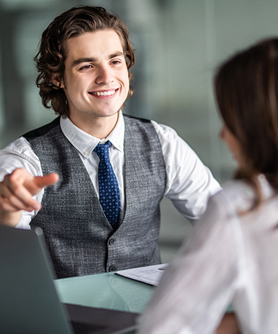 Ejecutiva de negocios gestionando un crédito documentario a chico vestido de corbata azul sonriendo 