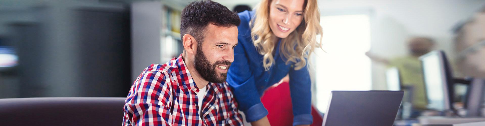 Chico y chica viendo el tipo de cambio de divisa online en un ordenador