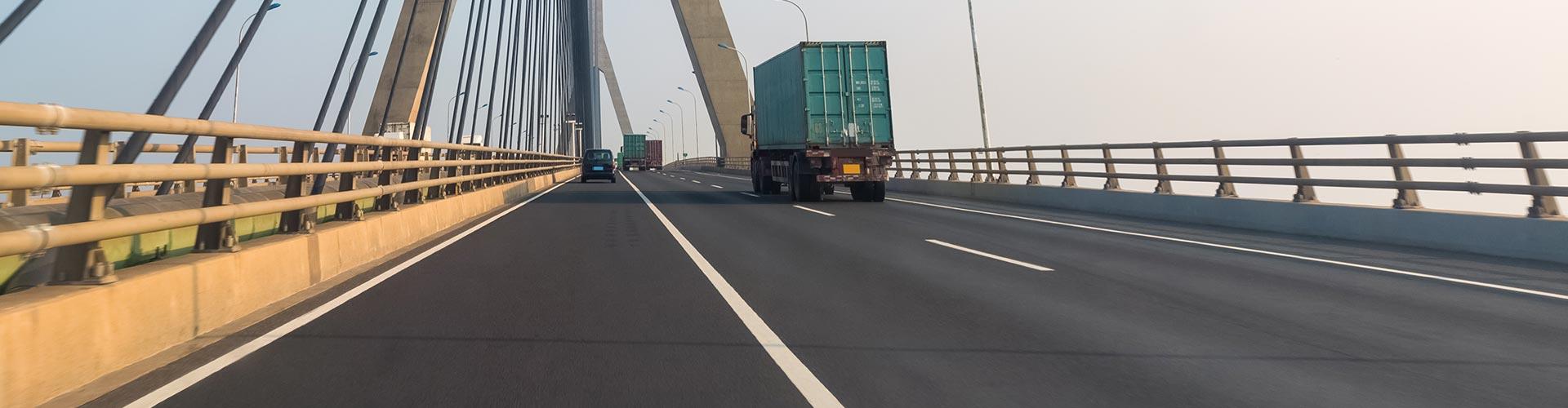 Seguro de Transportes - Carretera de una ciudad donde circulan camiones de transporte de mercancias junto a un puente