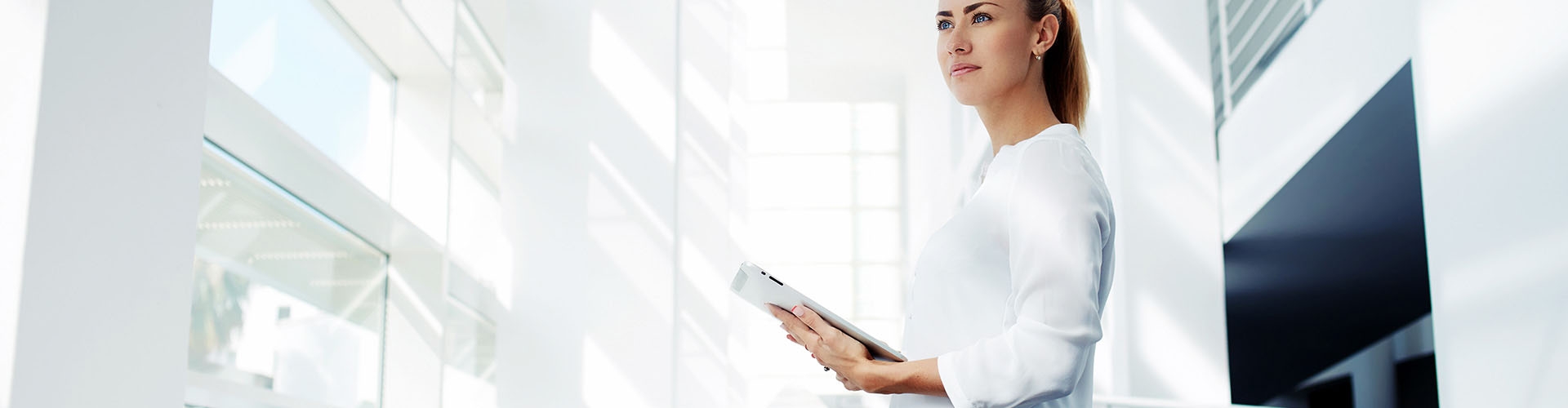  Eurocobro - Chica empresaria vestida con camisa blanca sujetando una tablet mirando al horizonte
