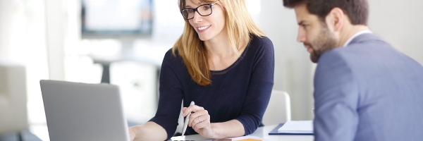 Tranquilidad en las operaciones de empresas con las remesas simples y documentarias de Globalcaja Remesas simples y documentarias de Globalcaja - Chica rubia sonriente con gafas negras atendiendo a chico de traje y barba, viendo las opciones de remesas