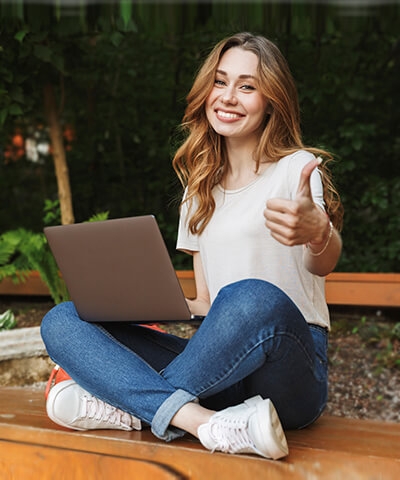 Ventajas para particulares - Joven chica sonriendo sentada utilizando un portátil