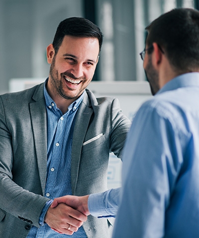 Financiamiento internacional factoring - Empresario vestido de traje formal, dando la mano a asesor internacional vestido de azul