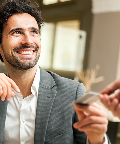 Empresario sonriente recibiendo una tarjeta de crédito empresa - Soluciones de pago para empresas