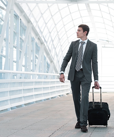  Opciones de Financiamiento para Empresas de  exportación e importación - Empresario vestido de traje, llevando su equipaje de mano en aeropuerto